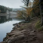 Lac de chaumeçon morvan : eau calme, berge boisée et barrage au fond